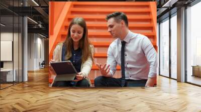 Image of young businessmen and colleague discussing document in laptop and touchpad at meeting Wall mural