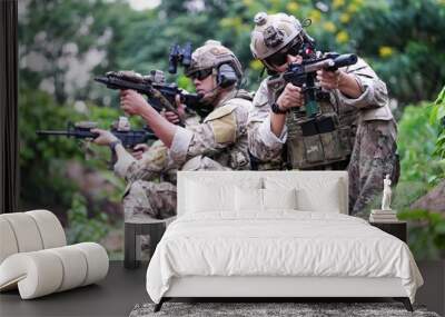 Military army soldiers tactical team, commando group moving cautiously in forest area, kneeling and looking around, covering comrades, controlling sectors. Commander showing halt or stop hand signal Wall mural