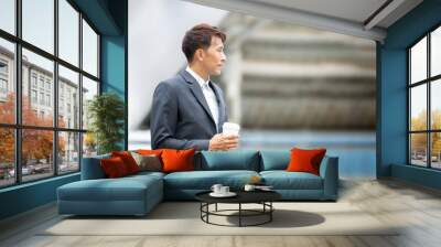 Side view of young businessman standing with coffee cup at outdoor  Wall mural