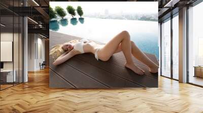 Young woman enjoying a sun, Slim young girl model in white bikini  by the pool. Wall mural