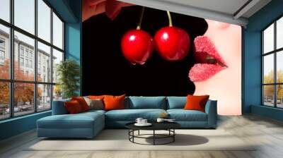 Beautiful young woman eating cherry. Sensual red lips in sugar isolated on black background. Wall mural