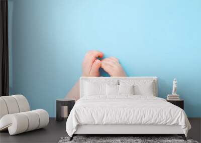 Baby hands on light blue table background. Pastel color. Closeup. Point of view shot. Top down view. Wall mural