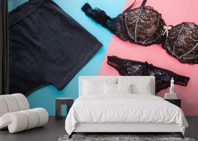 Man and woman black underwear on pink blue table background. Pastel color. Two sides. Closeup. Top down view.  Wall mural