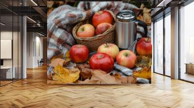 A cozy autumn picnic setting with fresh apples and a thermos in a basket on fallen leaves Wall mural