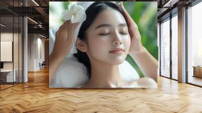 A serene woman enjoying a relaxing spa facial treatment surrounded by lush greenery and delicate flowers in a tranquil setting Wall mural