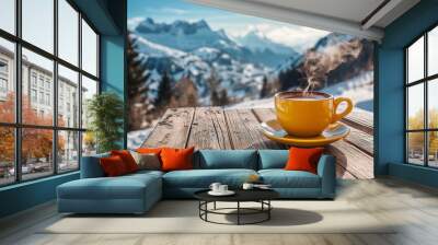 A steaming cup of coffee on a wooden table with snow-covered mountains in the background during a sunny winter day Wall mural