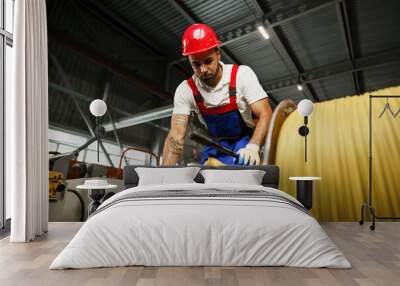 A young factory workman rolls heavy coil of electric cable Wall mural