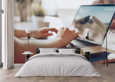 Close up of a woman typing on laptop while sitting at the table in office Wall mural