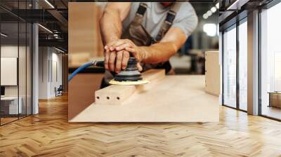 Close up of carpenter hands sanding wood with orbital sander at workshop Wall mural