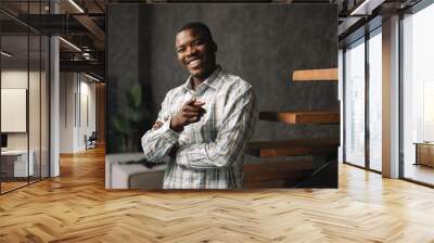 Confident young african businessman standing near wooden ladder portrait Wall mural