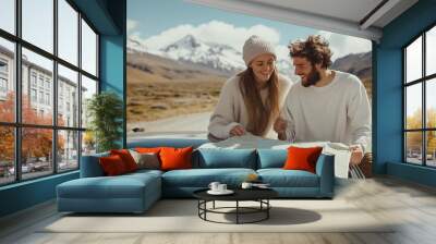 Couple exploring a mountainous region while studying a map during a sunny day on their road trip Wall mural