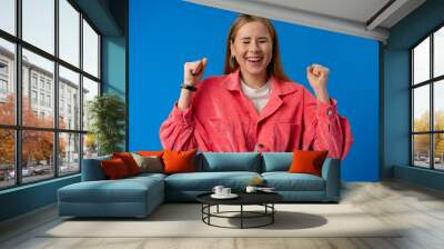 Excited thrilled woman portrait on blue studio background Wall mural