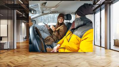 Family couple sitting in car in winter clothes iin snow forest Wall mural