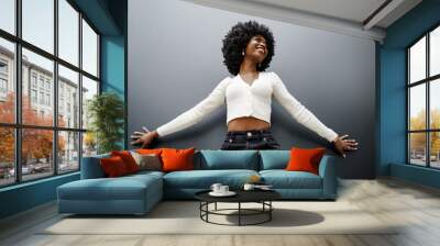 Fashionable young beautiful woman with afro hairstyle posing on the black wall Wall mural