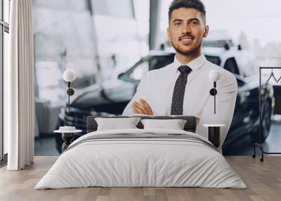 Friendly handsome car seller man standing in car salon Wall mural