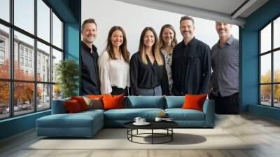 Group of six professionals smiling together in a modern office setting during daylight hours Wall mural