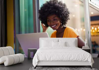 Happy beautiful young black woman using laptop in cafe Wall mural