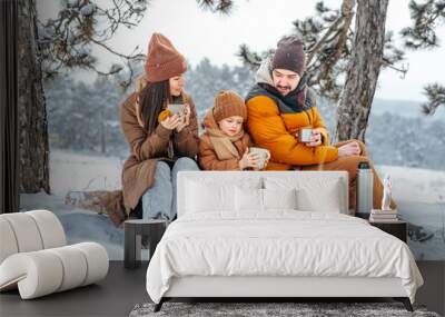 Happy family with cups of hot tea spending time together in winter forest Wall mural