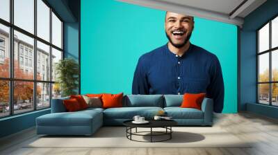 Joyful dark-skinned man laughing against turquoise background Wall mural