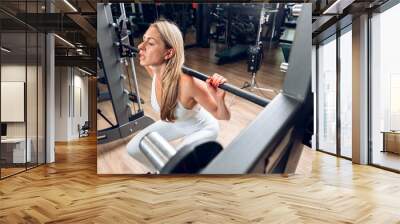 Middle-aged fitness woman doing squat exercise in a gym Wall mural