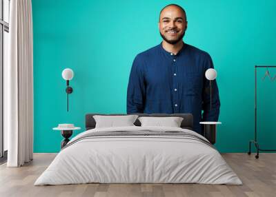 Portrait of a dark-skinned cheerful smiling man against turquoise background Wall mural