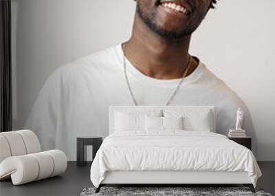 Portrait of a smiling young african man wearing white t-shirt standing over gray background Wall mural