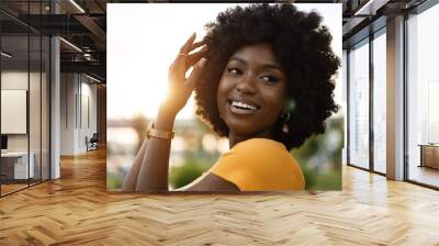 Portrait of a young african american woman smiling standing at the city. Wall mural