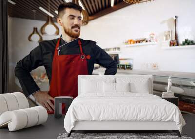 Portrait of a young man shopkeeper standing by meat stall in supermarket Wall mural