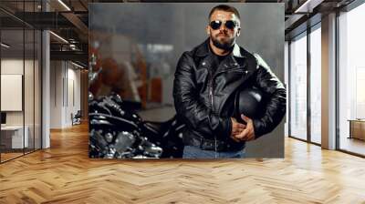 Portrait of bearded man motocyclist in dark sunglasses on dark background Wall mural