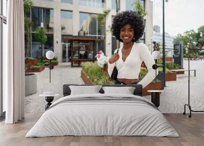 Portrait of young african woman with afro hairstyle smiling in urban background Wall mural