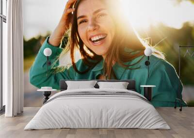 Portrait of young woman in green shirt smiling in a park Wall mural