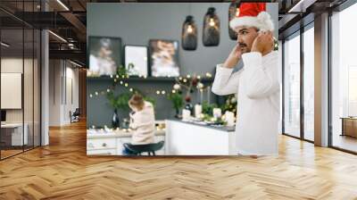 Side portrait of s man in Santa Claus hat standing indoors Wall mural