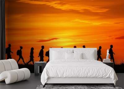 Silhouetted group of hikers walking against a vibrant sunset in the evening sky, creating a beautiful natural scene Wall mural