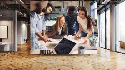 Team of diverse coworkers in modern office discuss their project together Wall mural