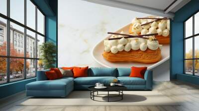 Two eclairs with white custard on whhite plate Wall mural