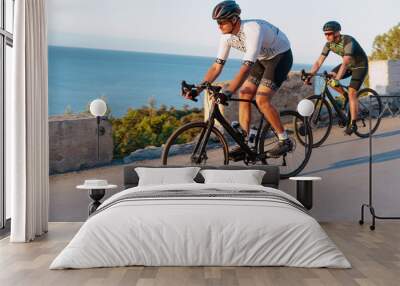 Two professional male cyclists riding their racing bicycles in the morning together Wall mural