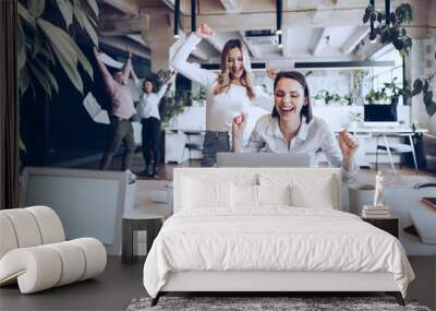 Two young happy businesswomen celebrating project success in office Wall mural