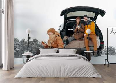 Winter portrait of a family sit on car trunk enjoy their vacation in forest Wall mural