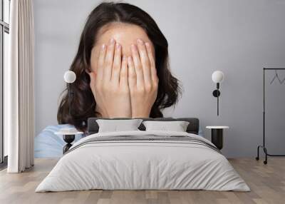 Woman covering her face with both hands Wall mural