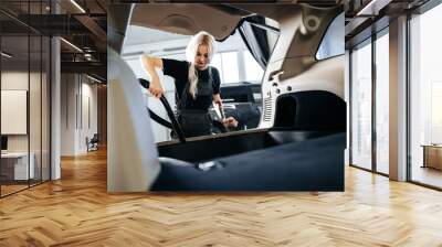 Worker woman vacuum cleaning dust interior inside car in car wash. Wall mural