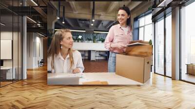 Young businesswoman holding box of personal belongings about to leave office after quitting job Wall mural