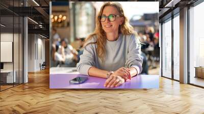 Young casual woman sitting at the table in coffeeshop Wall mural