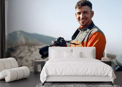 Young man traveler taking photos of mountains with professional camera Wall mural