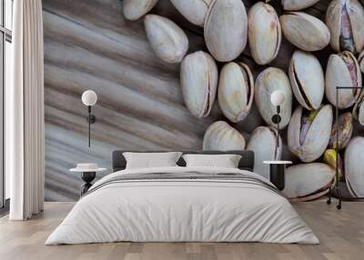 Lots of pistachios in their shell on a wooden chopping board. Natural, soft light Wall mural