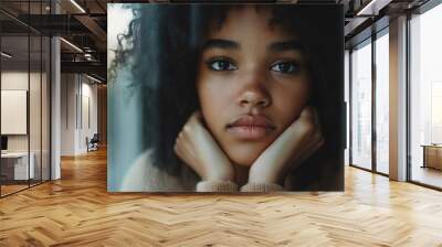 A close-up shot of a woman with her hand on her chin, lost in thought Wall mural