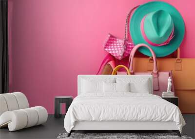 A collection of accessories including a hat, handbag, wallet, and purse on a bright pink background Wall mural