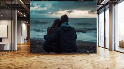 A couple sitting on a rocky beach, enjoying the ocean view Wall mural