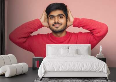 A man wearing a bright red sweater covering his ears, likely due to loud noise or discomfort Wall mural