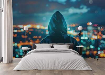 A person in a hoodie looking out over a city at night. Suitable for urban lifestyle concepts Wall mural