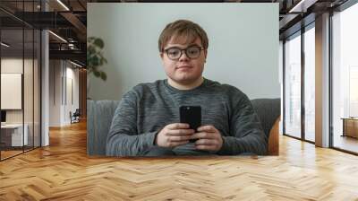 A person sitting on a couch holding a cell phone, perfect for depicting modern life Wall mural